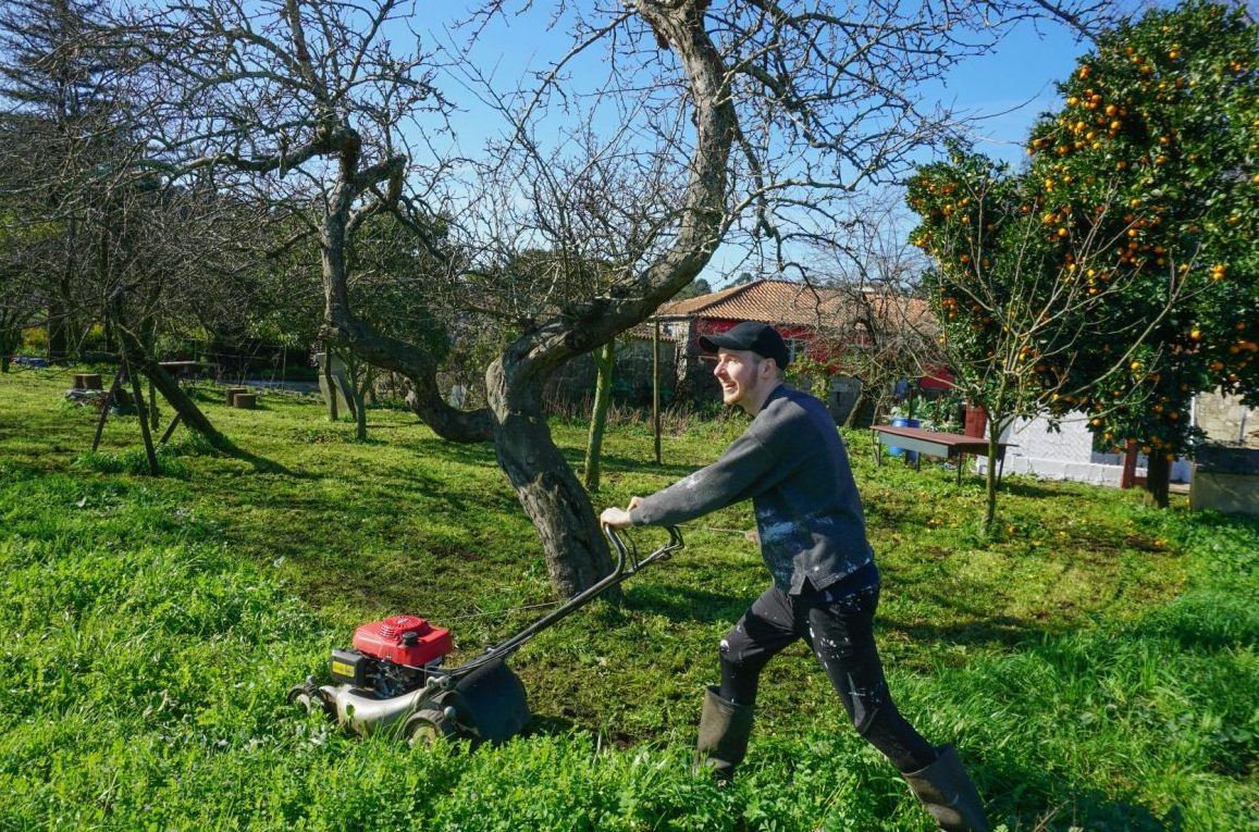 Un homme tond la pelouse avec une tondeuse à gazon